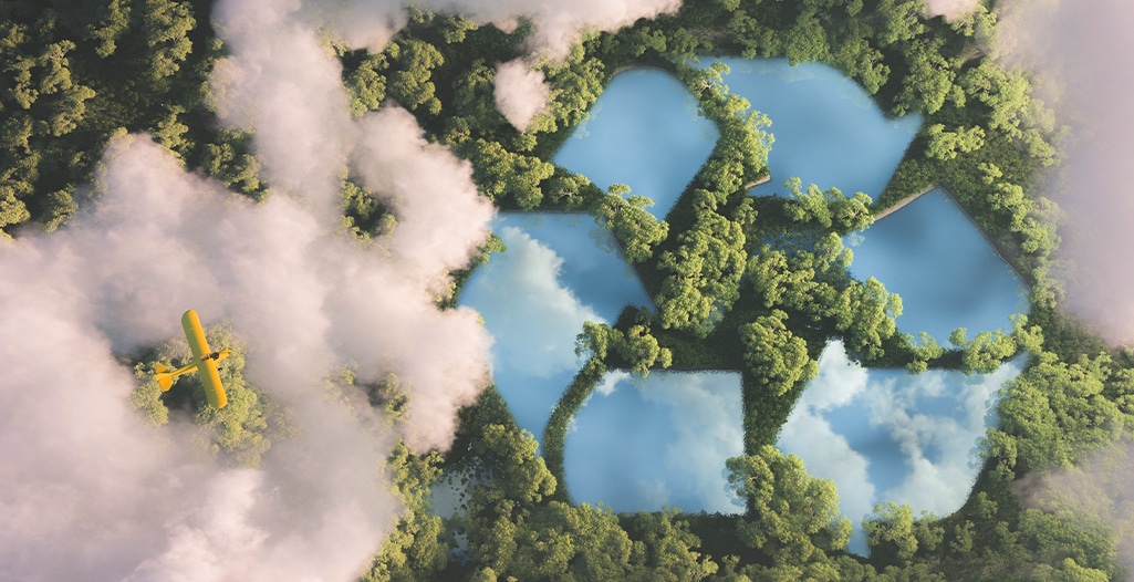 Recyclyling sign in a lake shape in a dense forest view above clouds with yellow plane.
