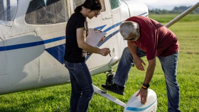 Couple prepares small airplane for flight.