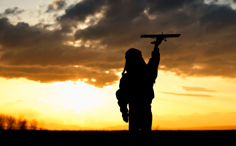 child flying model aircraft at sunset