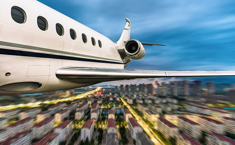 business jet flying over city