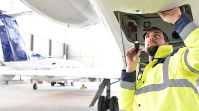 Airport worker completes an aircraft safety check in hangar